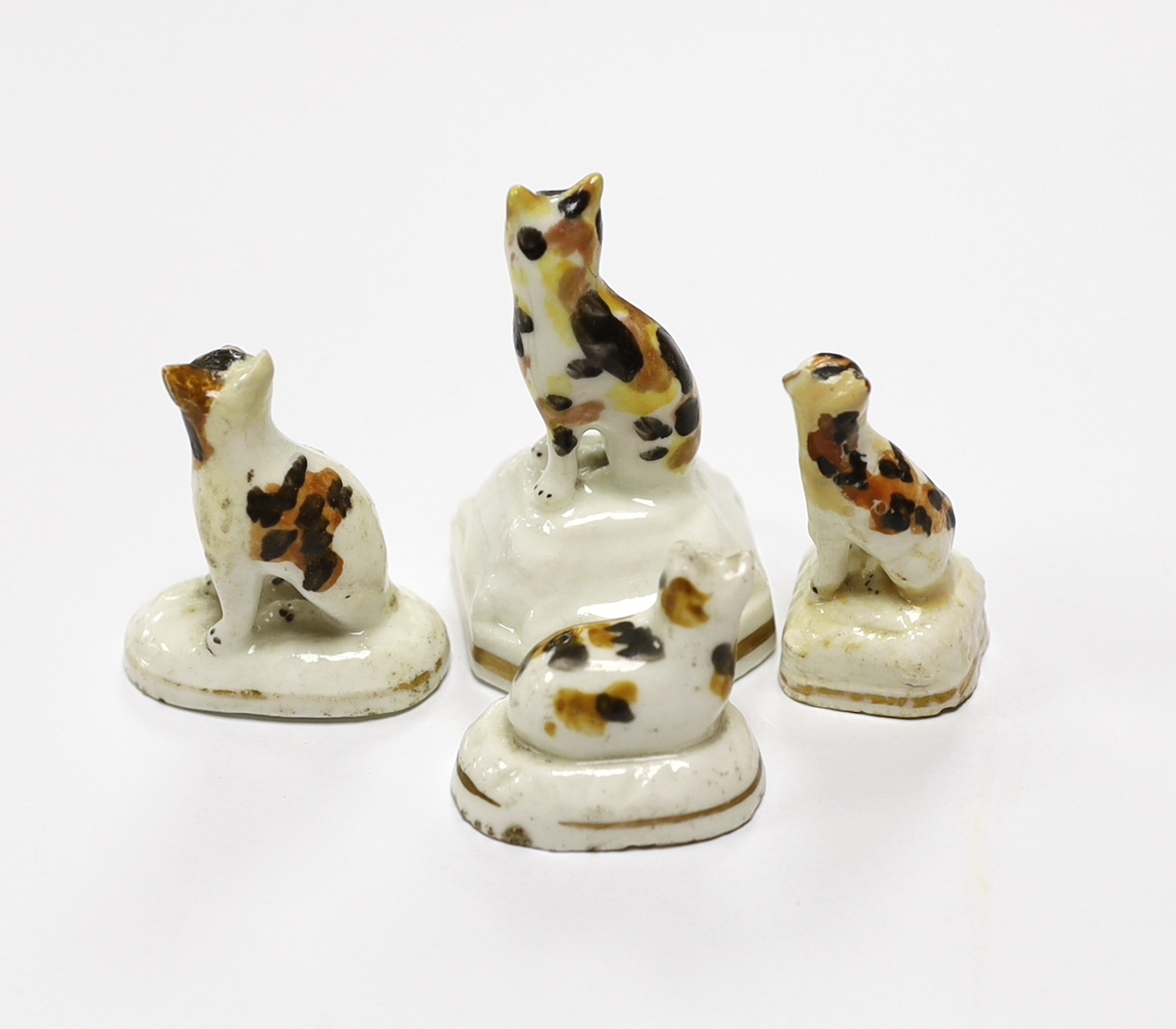 Four Staffordshire porcelain models of tortoiseshell cats, c.1830-50, three seated on shaped bases, the third model is a kitten on an oval base, tallest 5.3 cm